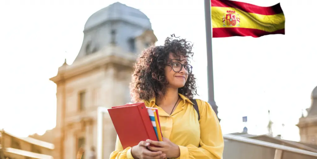 Estudiante colombiano en una universidad en España con libros y laptop.